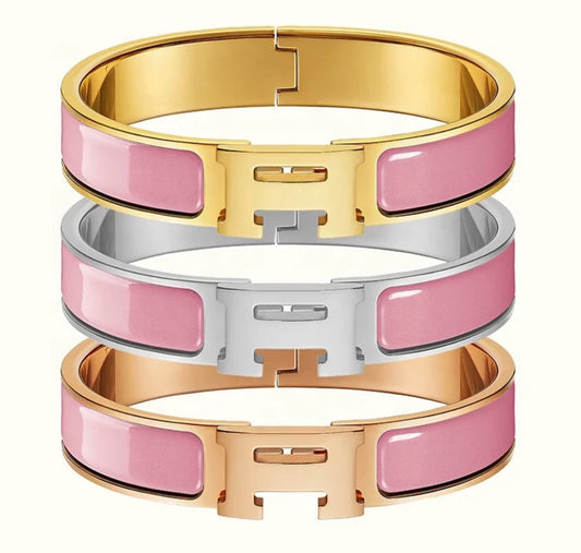 Three pink and gold bracelets stacked on a white background